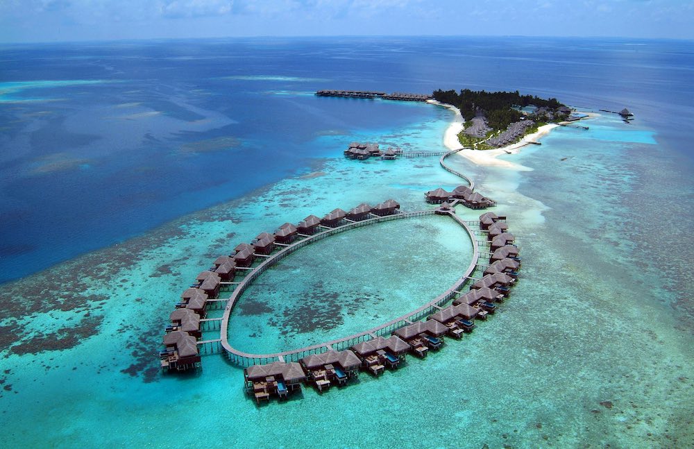 Coco Bodu Hithi viewed from above, with overwater villas around a lagoon