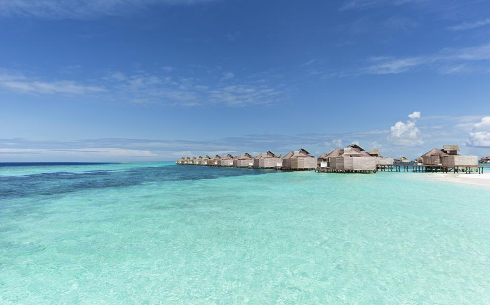 A line of Six Senses Laamu overwater villas across a clear lagoon